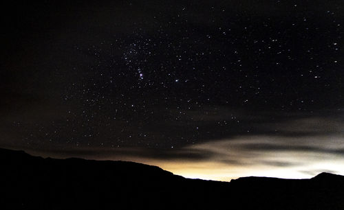 Low angle view of silhouette mountain against sky at night