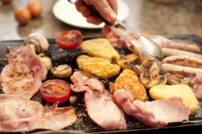 Cropped hand of man over cooking food