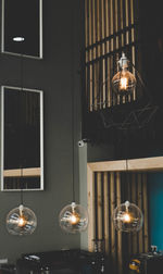 Low angle view of illuminated pendant light hanging on wall at home