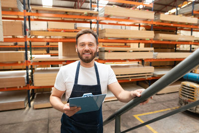 Portrait of businessman holding clipboard in factory