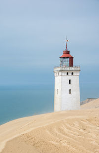 Lighthouse on beach against sky