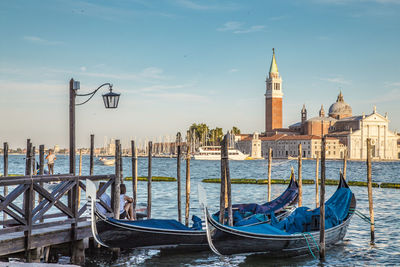 Boats moored in canal with city in background