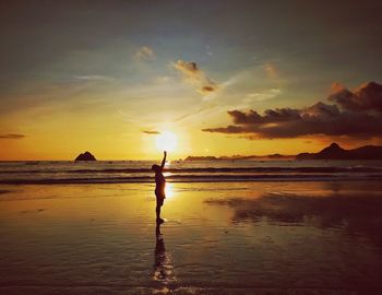 Silhouette person on beach against sky during sunset