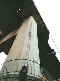 Low angle view of man standing on bridge against sky