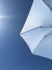 Low angle view of parasol against clear blue sky