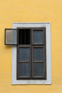 Close-up of window amidst yellow wall