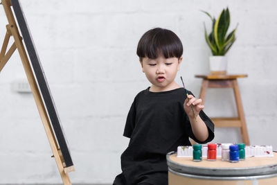 Side view of boy painting on canvas at home