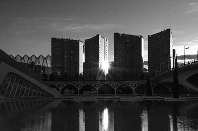 Bridge over river by buildings against sky in city