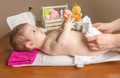 Woman changing diaper of baby girl at home