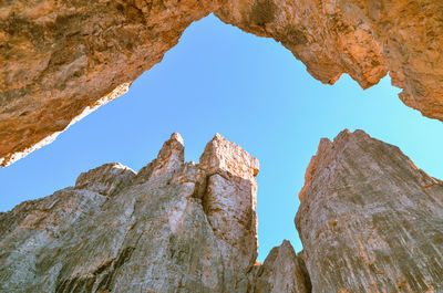 Low angle view of rock formation against clear blue sky