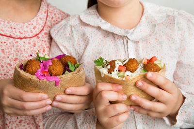 Close-up of the hands of two girls holding falafel sandwiches