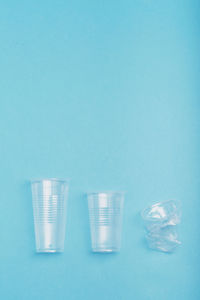 Squashed empty plastic cups put in a row, over blue background. collecting plastic waste