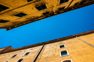 Low angle view of old building against clear blue sky