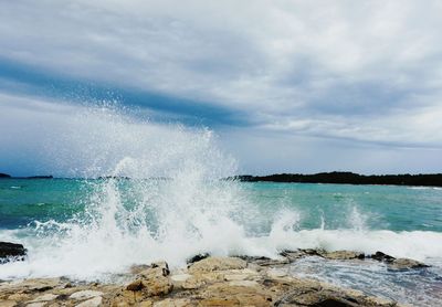 Waves splashing on sea against sky