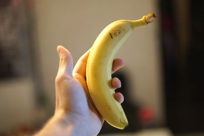 Cropped hand holding banana at home