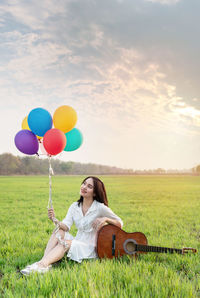 Full length of woman with balloons in field