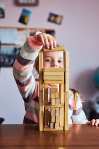 Little girl preschooler playing with wooden blocks toy building a tower. concept of building a house