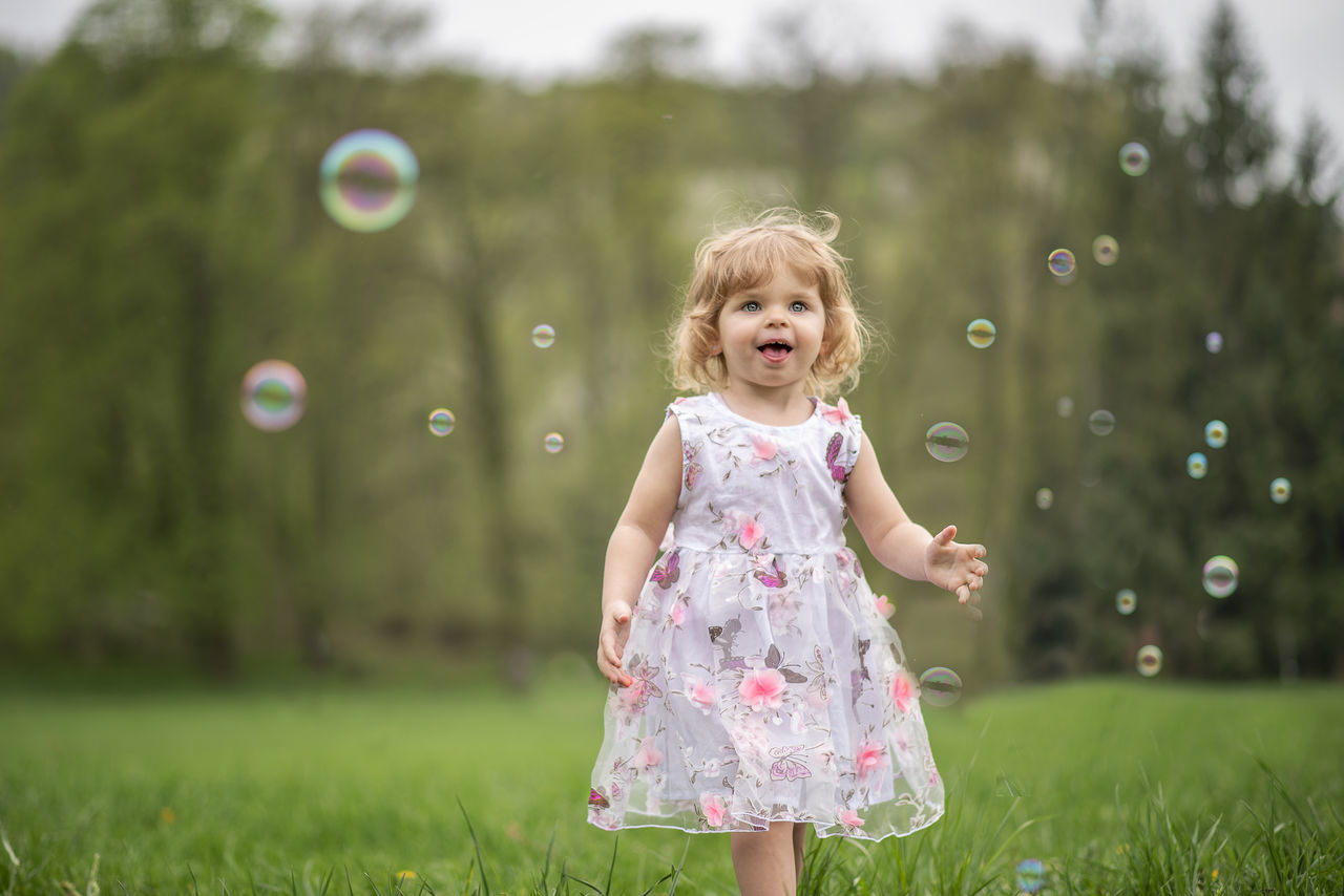 childhood, child, real people, innocence, one person, cute, females, grass, girls, plant, women, focus on foreground, bubble, day, three quarter length, leisure activity, land, outdoors, hairstyle