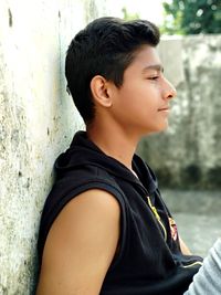 Side view of boy looking away against wall