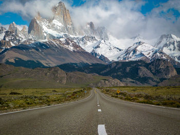 Road by snowcapped mountains against sky