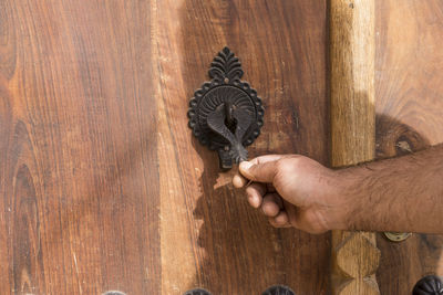 Cropped hand of man holding door knocker