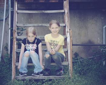 Full length portrait of sisters sitting on steps