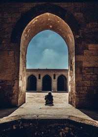 Rear view of woman sitting on old building