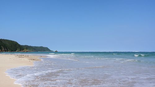 Scenic view of beach against clear blue sky