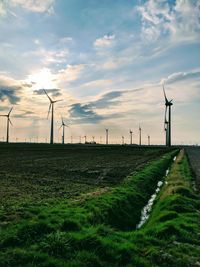 Windmills on field against sky during sunset