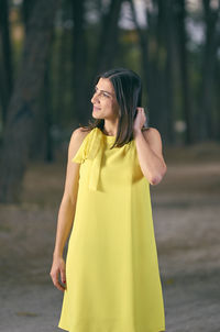 Happy young woman standing against yellow tree