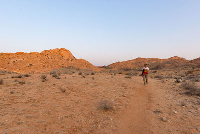 Female tourist standing at desert in namib-naukluft national park against clear sky