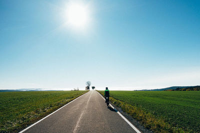 People walking on field against clear blue sky