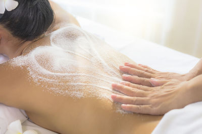 Cropped hands of massage therapist massaging shirtless woman back