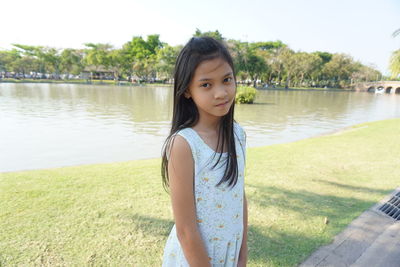 Portrait of young woman standing against lake