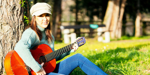 Portrait of woman playing guitar at park