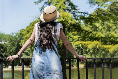 Rear view of woman standing by railing against trees