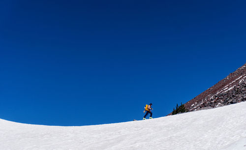 Low angle view of hiker on snow against blue sky