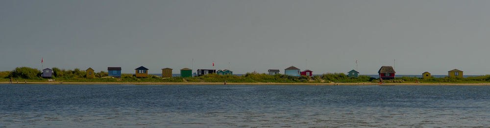 Sea by houses against clear sky