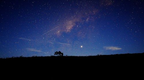 Low angle view of silhouette landscape against star field at night