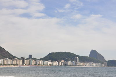 Sea by buildings against sky in city