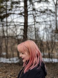 Woman with dyed hair standing in forest