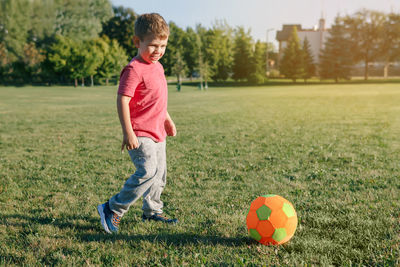 Full length of boy playing with ball on grass