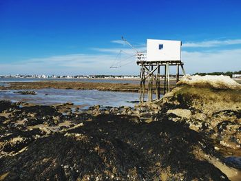 Lifeguard hut on beach against blue sky