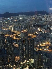 Illuminated modern buildings in city against sky at night