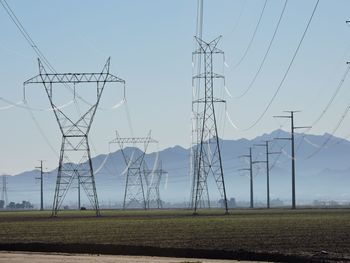 Electricity pylon on field against sky