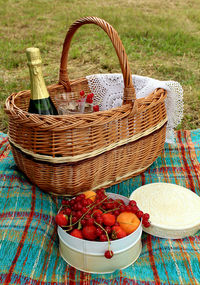 Picnic basket with a bottle of wine and apricot and berries in a round tin