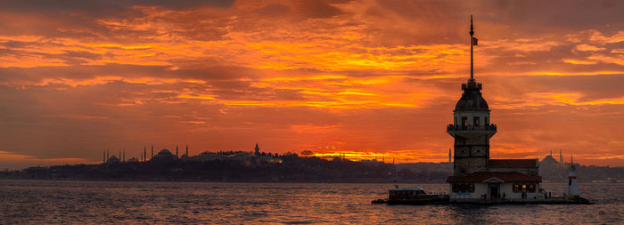 Maiden tower in sea against sky during sunset