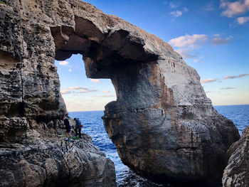 Rock formation by sea against sky