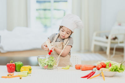 Midsection of baby girl eating food in kitchen