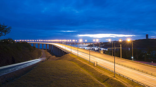 Light trails on road in city against sky at night